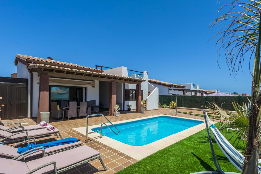 a villa with a swimming pool and a house at Villa Illusion by Golf Club in Caleta De Fuste
