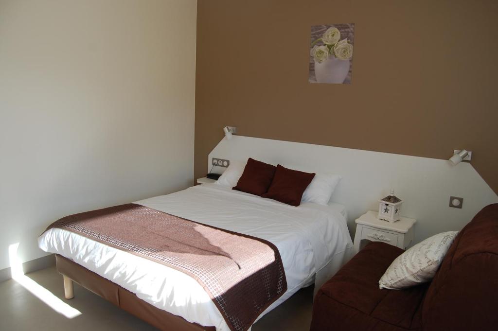 a bedroom with a white bed and a couch at Hôtel L'Escale Périgueux Notre Dame in Notre-Dame-de-Sanilhac