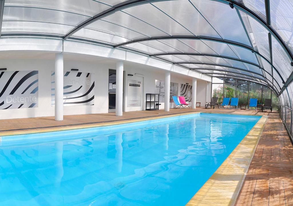 a swimming pool with a metal canopy over a swimming pool at Golden Tulip Pornic Suites in Pornic