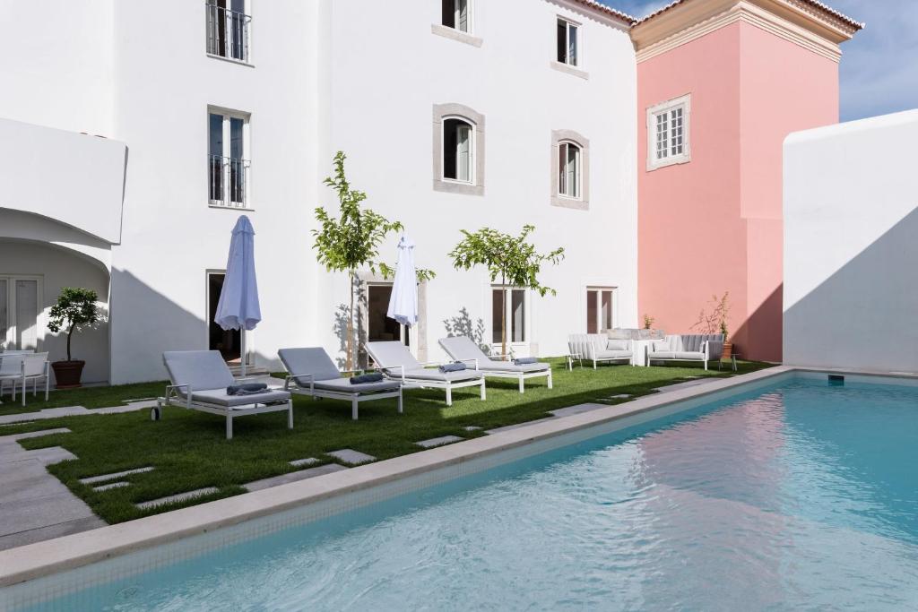 a pool in front of a building with chairs and umbrellas at Travassos 11 in Elvas