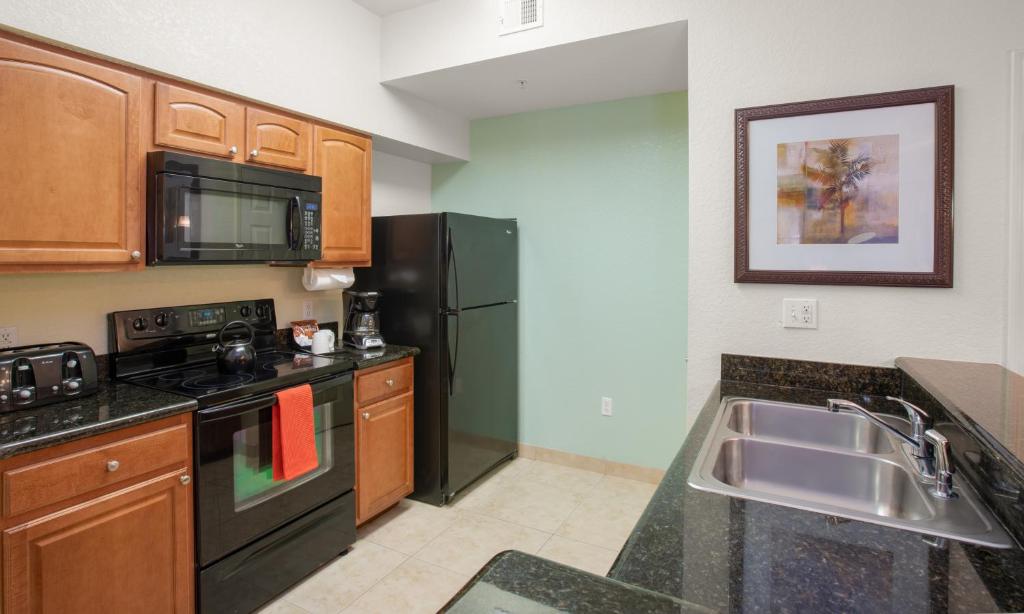 a kitchen with a sink and a black refrigerator at Lake Buena Vista Resort Village and Spa, Near Disney in Orlando