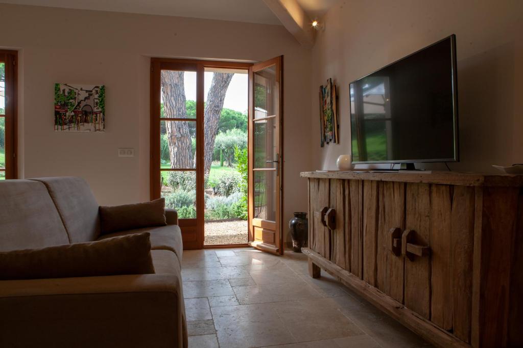 a living room with a flat screen tv on a wooden cabinet at Les Pins de l&#39;Escalet in Ramatuelle