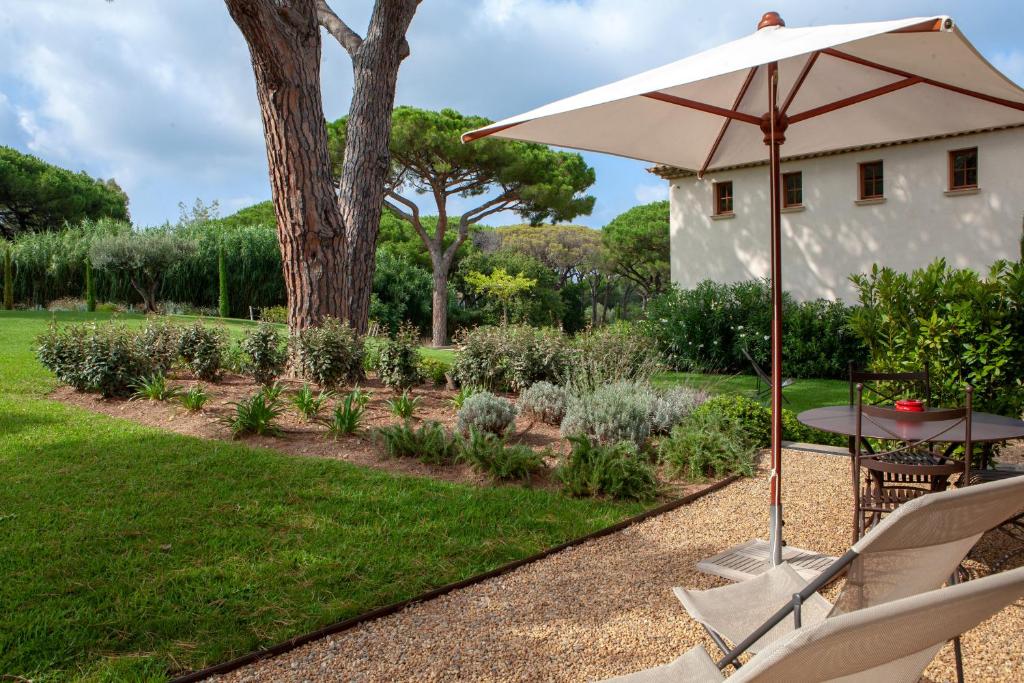 a table and chairs with an umbrella in a garden at Les Pins de l&#39;Escalet in Ramatuelle