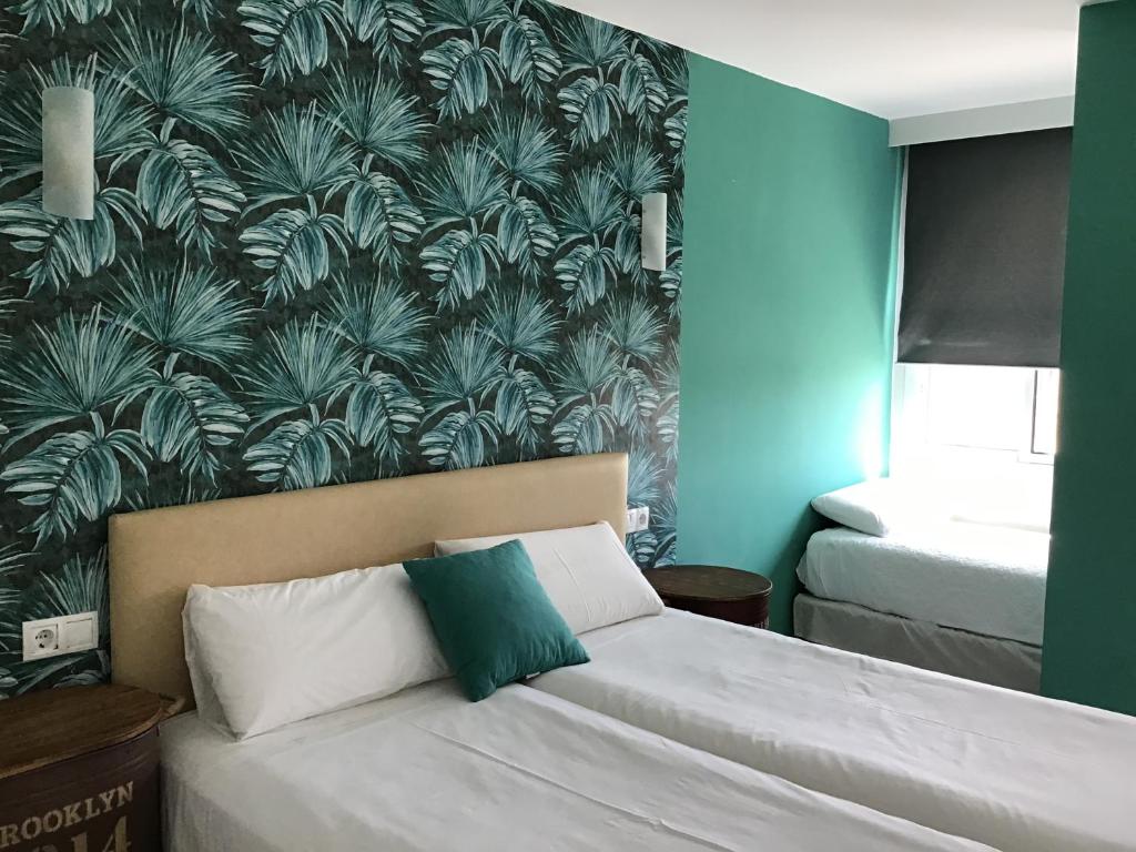 a bedroom with a bed and a wall with a plant wallpaper at Hotel Nómadas in Vejer de la Frontera