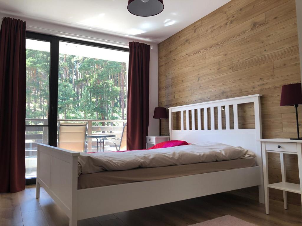 a bedroom with a white bed and a large window at Borov park 3 in Velingrad