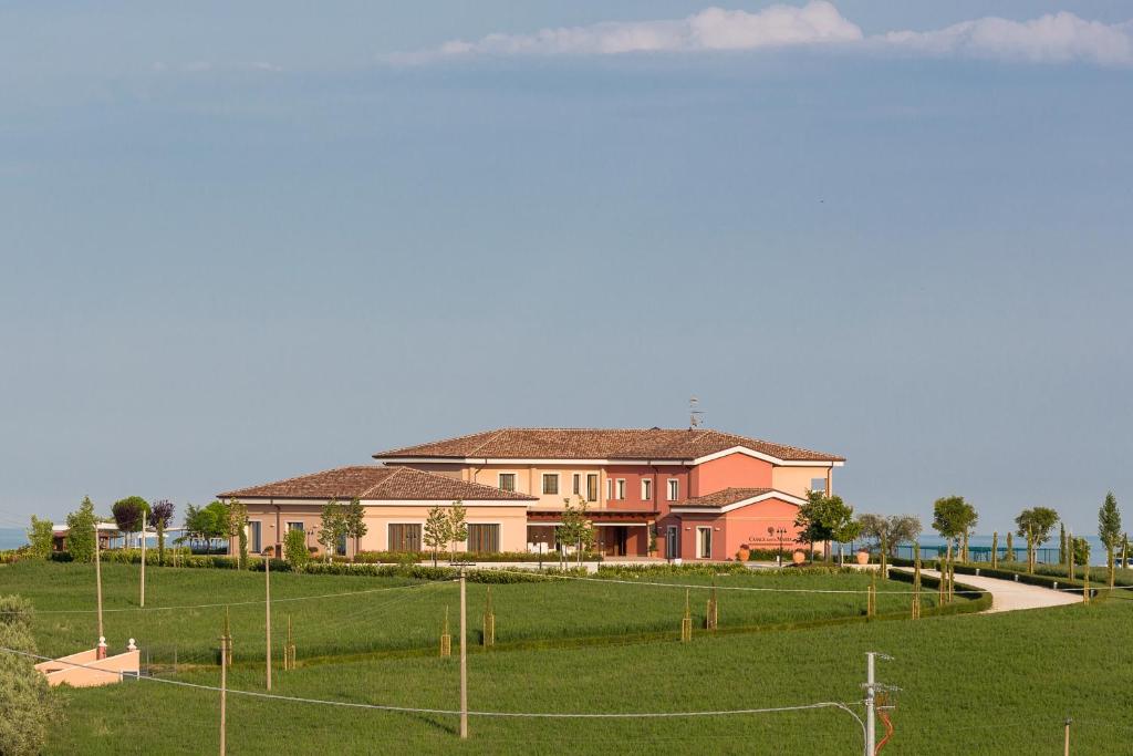una grande casa rosa con un campo di fronte di Casale Santa Maria Country House a Mosciano SantʼAngelo