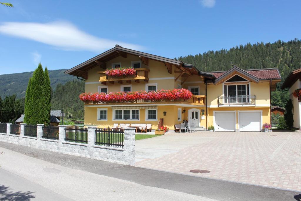 Casa amarilla con balcón con flores rojas en Haus Anni, en Radstadt