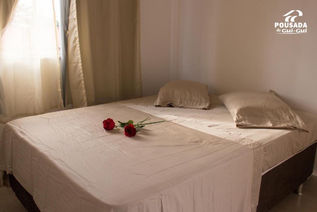 a bed with two roses on top of it at Pousada do Gui-Gui Aeroporto in Goiânia