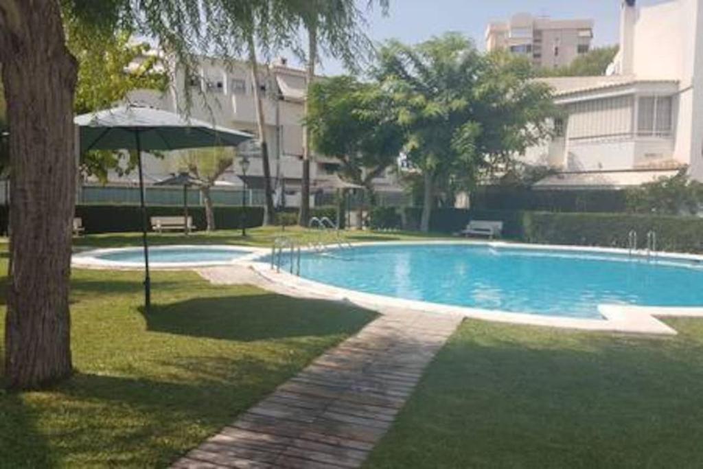 a swimming pool with an umbrella next to a building at Bungalow sol y playa in El Campello