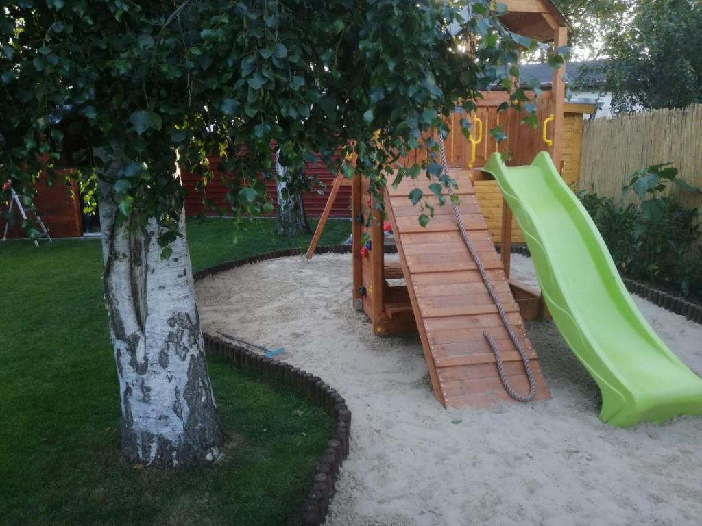 a playground with a green slide next to a tree at Haus Ostwind in Zinnowitz