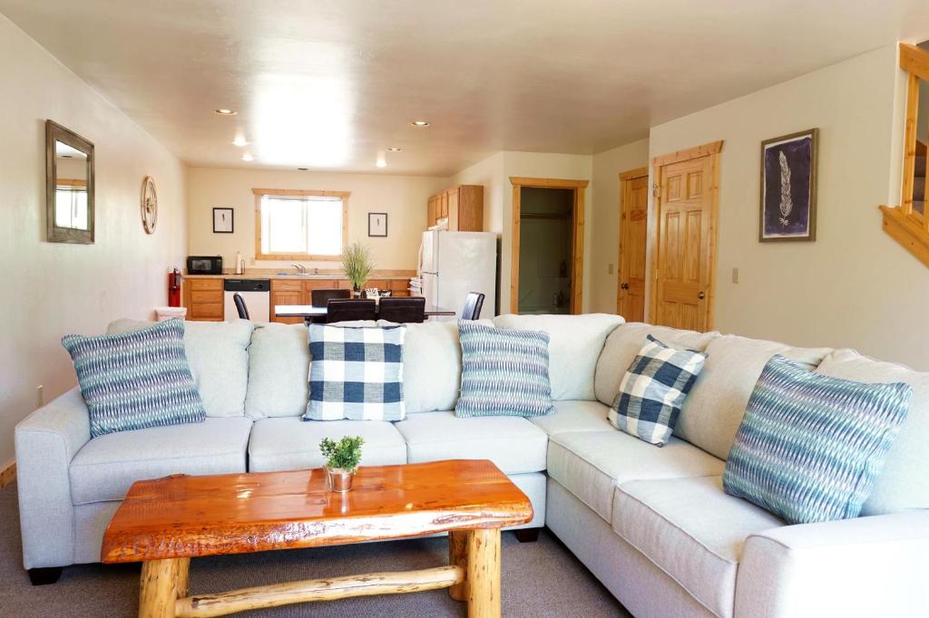 uma sala de estar com um sofá branco com almofadas azuis em The Aspen Condos em West Yellowstone