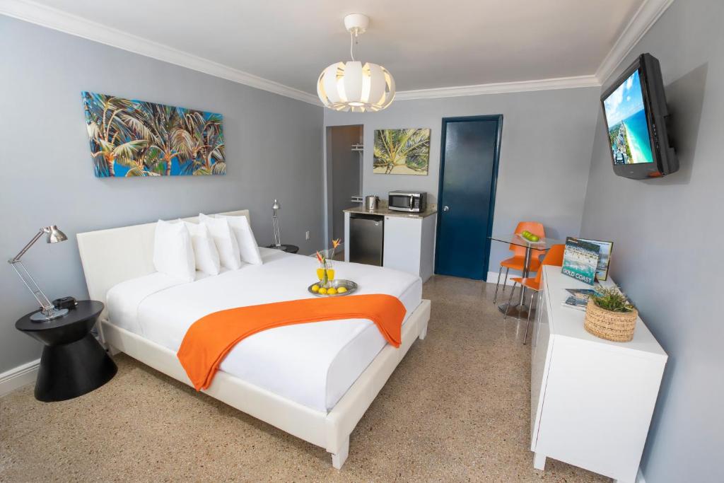 a bedroom with a large white bed with an orange blanket at Hollywood Beach Suites and Hotel in Hollywood