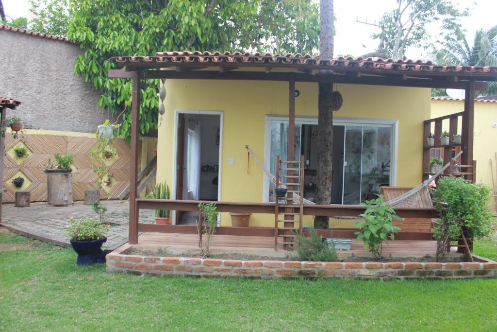 a house with a wooden deck in the yard at Hostel Luz in Anchieta