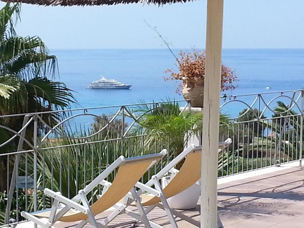 a pair of chairs on a balcony with a cruise ship in the ocean at Residence Porto Ulisse in Parghelia