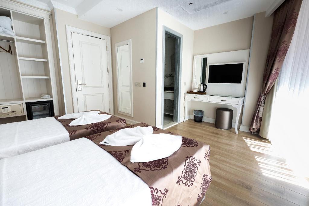 a hotel room with two beds and a flat screen tv at Villa Sweet Hotel in Istanbul