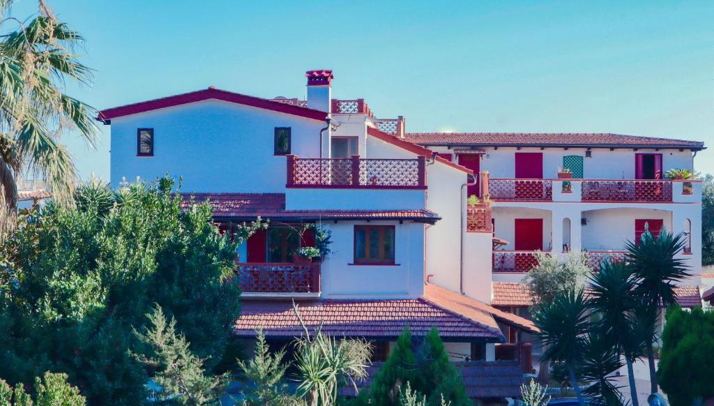 een wit huis met rode balkons en bomen bij Masseria Torca - Isca in Massa Lubrense