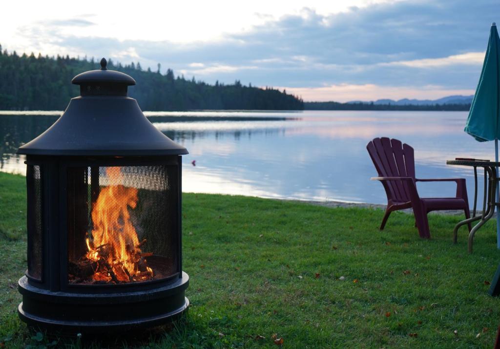 a lantern sitting on the grass next to a lake at Le Cent in Saguenay