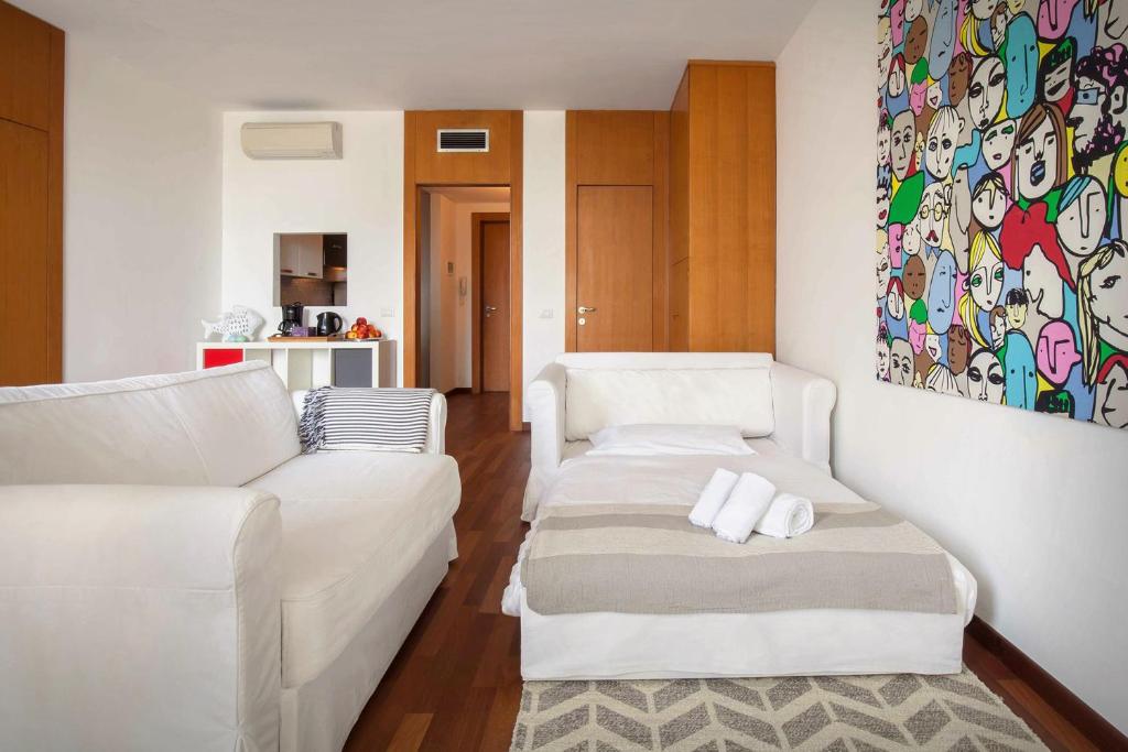 una sala de estar con 2 sofás blancos y una pintura en LA CHIARETTO SUITE en Bardolino