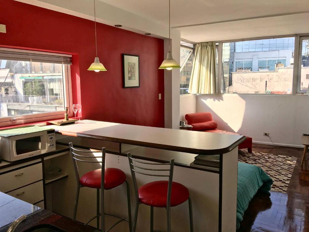 uma cozinha com paredes vermelhas e uma mesa e cadeiras em Bright, open view studio in Retiro em Buenos Aires