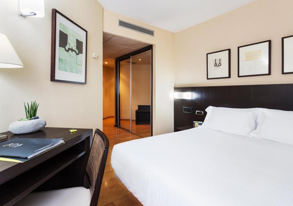 a hotel room with a bed and a desk and a bed and a table at Hotel Sercotel Tudela Bardenas in Tudela