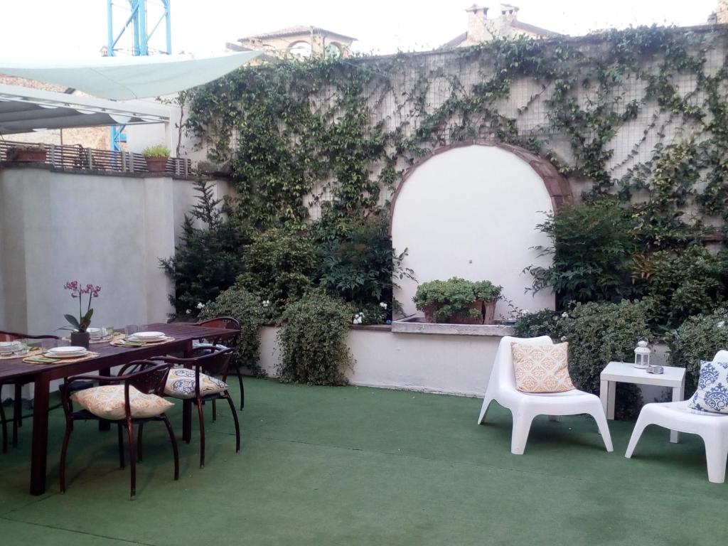 an outdoor patio with tables and chairs and an ivy covered wall at B&B Palazzo Bianchi in Parma