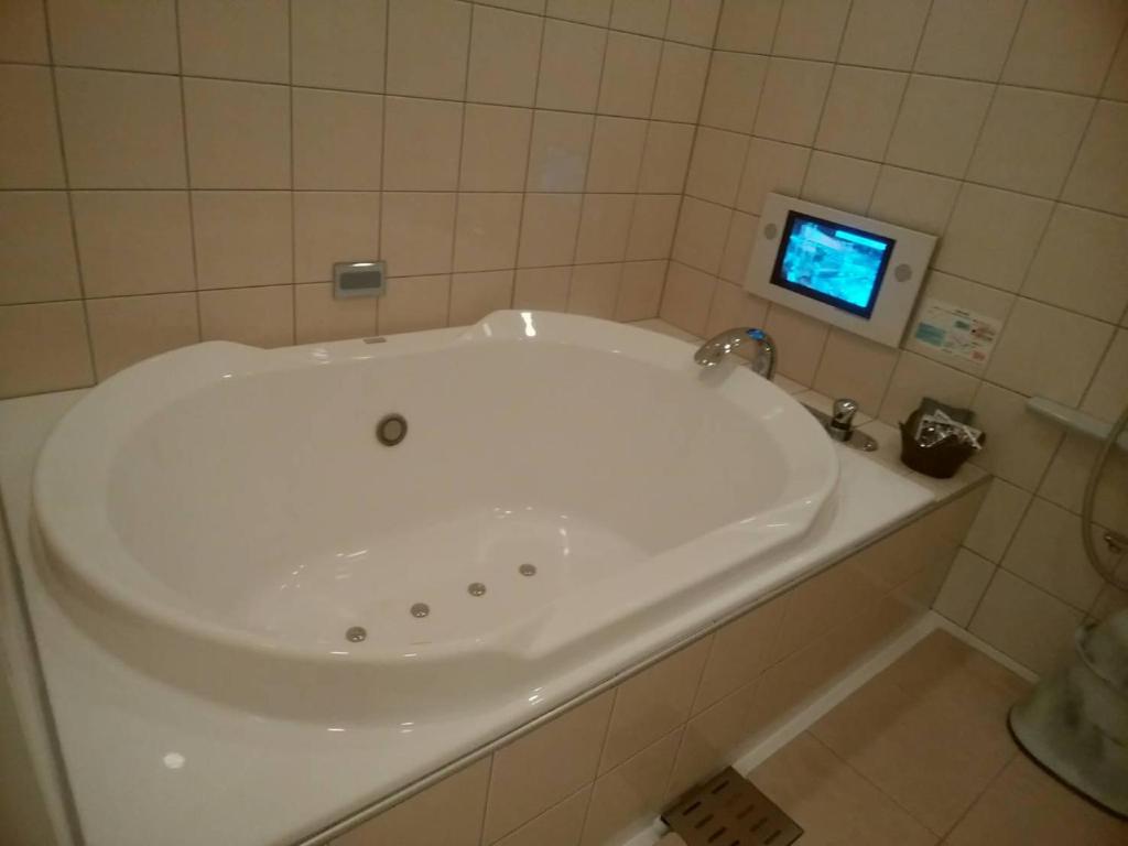 a white tub in a bathroom with a tv at Hotel PLAISIR (Adult Only) in Hiroshima