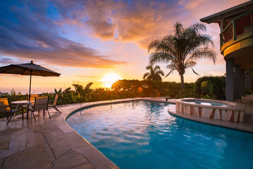 une piscine avec vue sur le coucher du soleil en arrière-plan dans l'établissement Affordable Luxury on One Acre, à Kailua-Kona