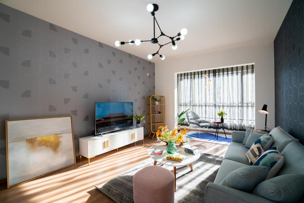 a living room with a blue couch and a tv at Harbin Nangang·Haxiwanda in Harbin