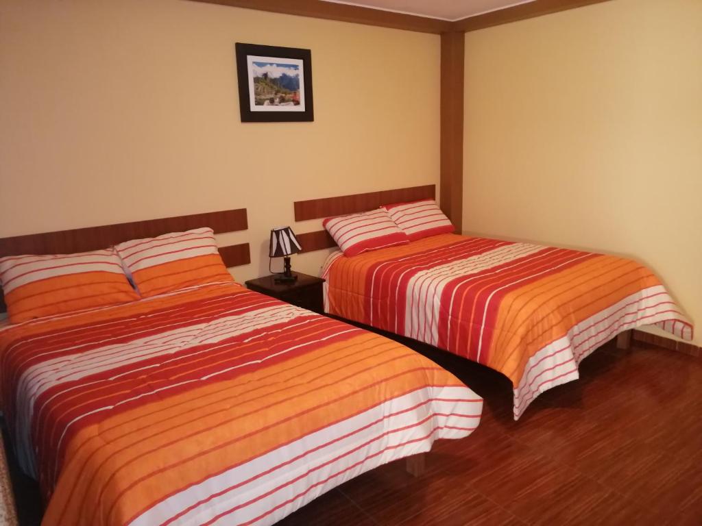 twee bedden naast elkaar in een slaapkamer bij Nasca Travel One Hostel in Nazca