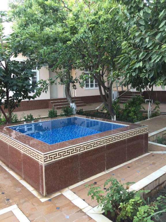 a swimming pool in a brick wall with trees at Munis in Samarkand