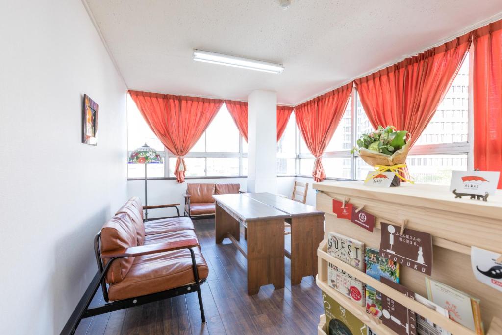 - un salon avec des rideaux rouges, une table et des chaises dans l'établissement Almas Guest House(アルマス）, à Nagasaki