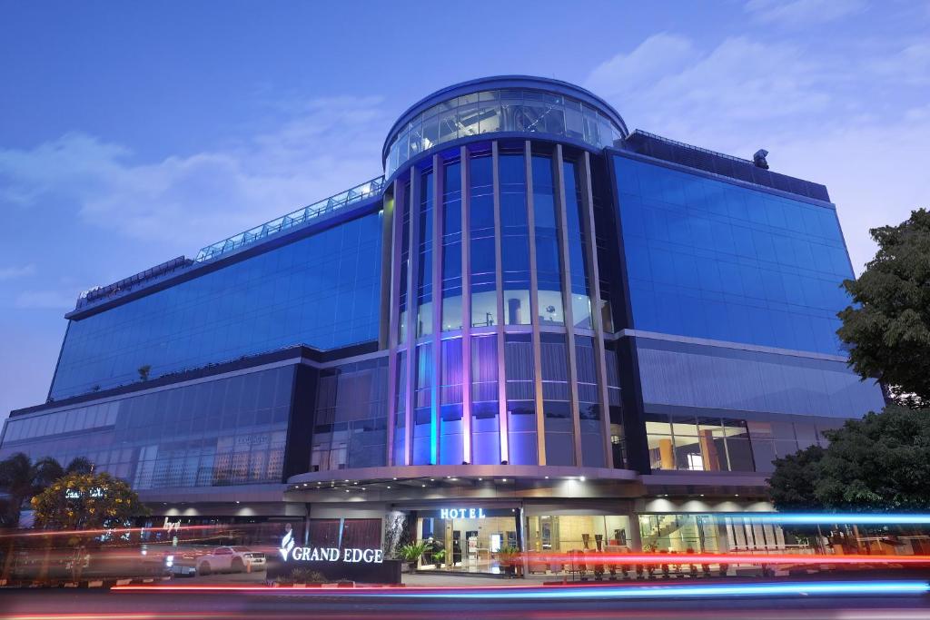 - un grand bâtiment en verre avec des lumières bleues dans l'établissement Grand Edge Hotel Semarang - CHSE Certified, à Semarang