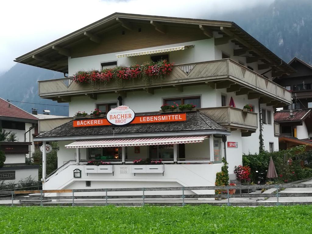 Un grand bâtiment blanc avec des fleurs sur les fenêtres dans l'établissement Ferienwohnung Bacher, à Mayrhofen