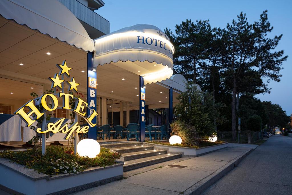 een hotelgebouw met een levend bord voor het hotel bij Hotel Villa Aspe in Bibione
