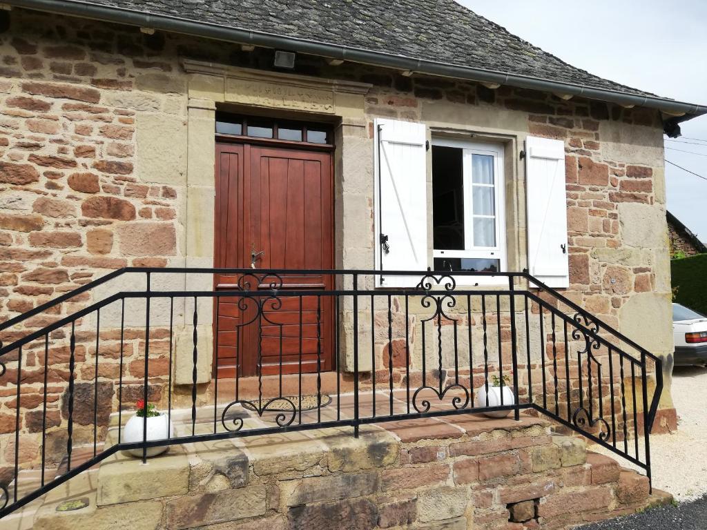 uma casa com uma porta de madeira e uma varanda em Lanteuil Maison de vacances à côté de brive et collonge la rouge em Lanteuil