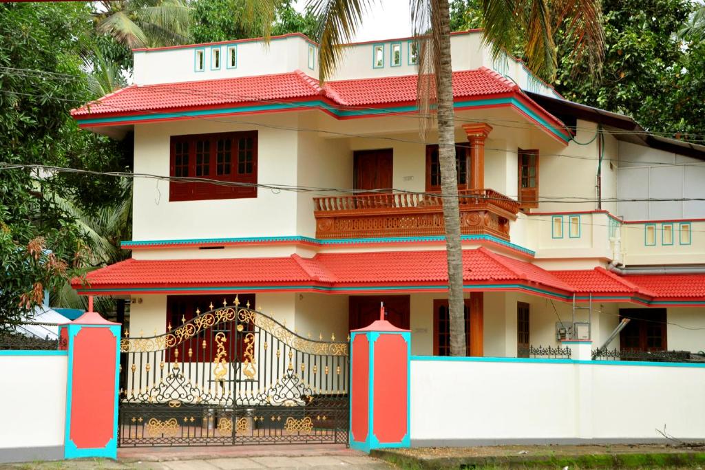 a white house with red roof at Krishnendu Homestay outer ring road north nada guruvayur in Guruvāyūr