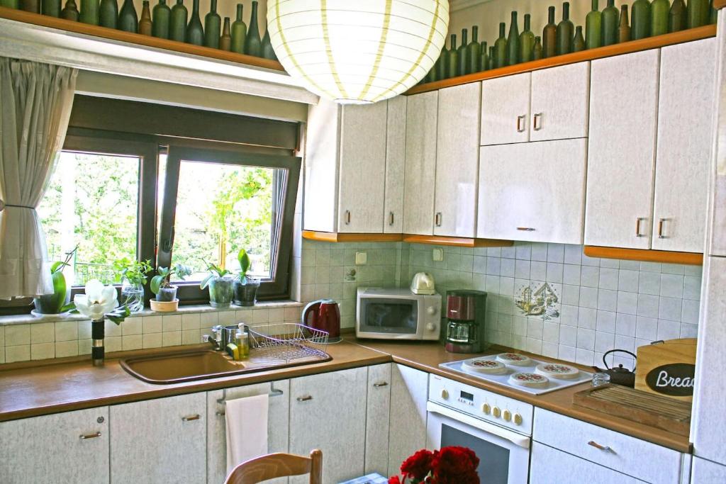 a kitchen with white cabinets and a sink and a microwave at Victoria's Apartment in Thessaloniki