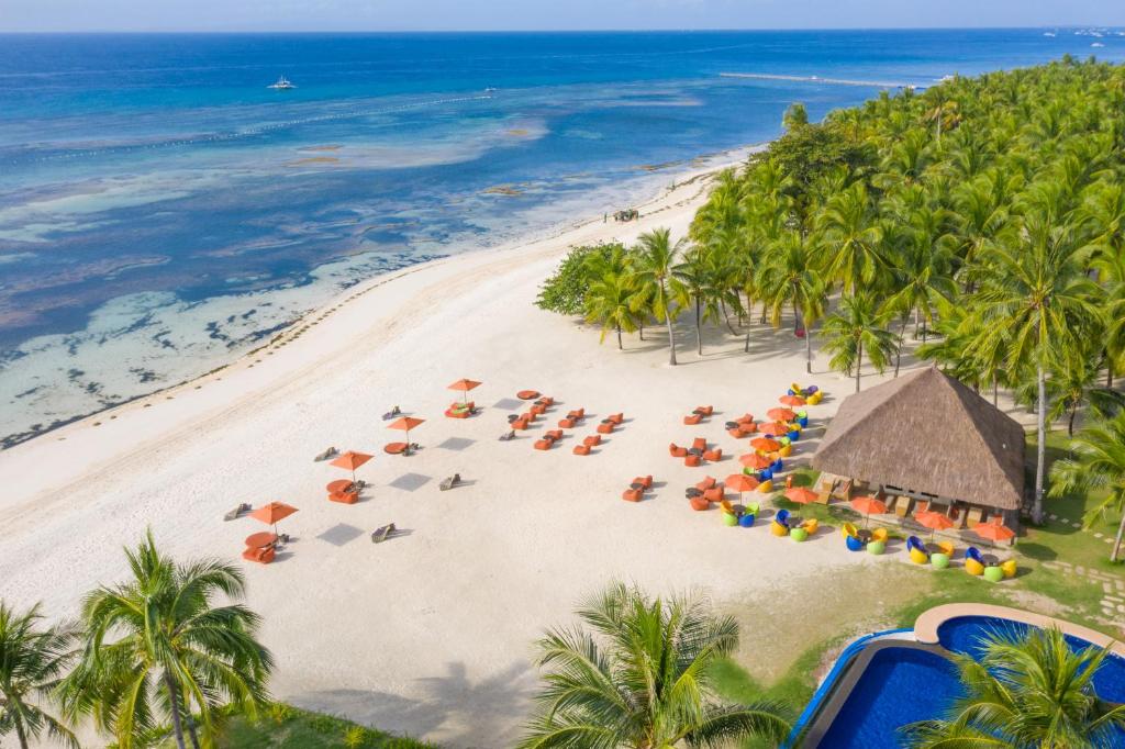 Oceanica Resort Panglao - formerly South Palms Resort Panglao في بنغلاو: اطلالة جوية على شاطئ فيه نخيل ومظلات