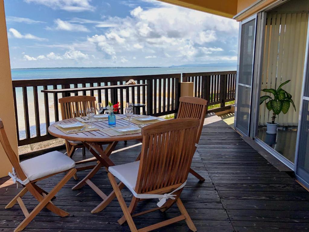 een tafel en stoelen op een balkon met uitzicht op de oceaan bij ポンツーン in Ishigaki Island