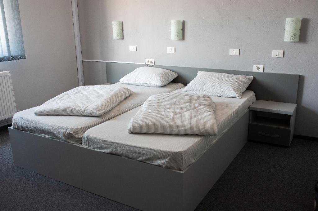 two beds in a room with white sheets and pillows at Pensiunea Vlad in Arad