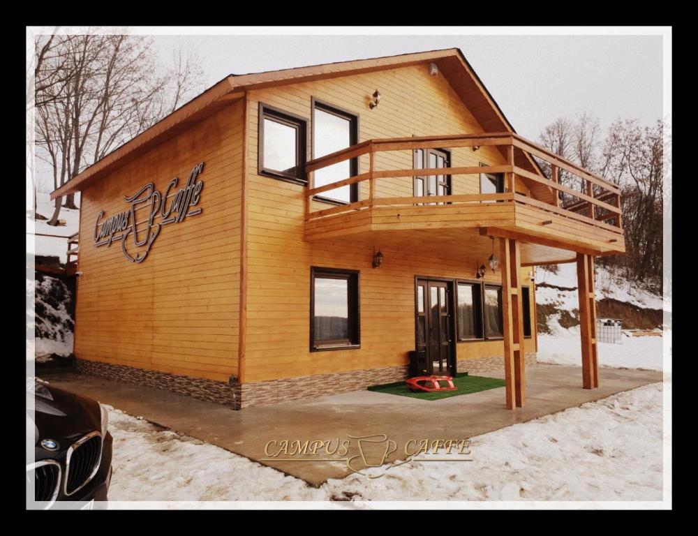a large wooden house with a deck in the snow at Cabana Campus Caffe in Buzău