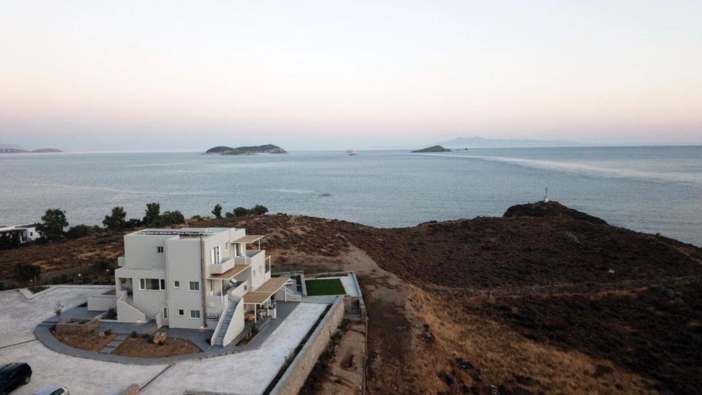 a white house on a hill next to the ocean at Pharos Apartments in Gavrio