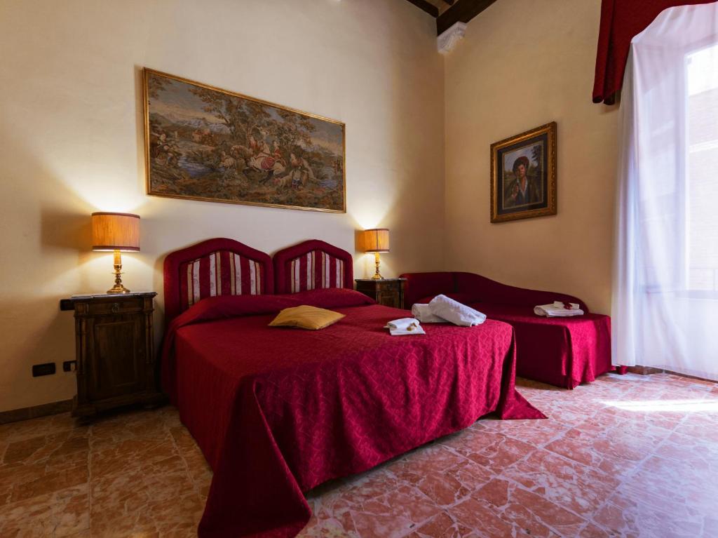 een slaapkamer met 2 bedden met rode lakens en een schilderij bij B&B Siena In Centro - Diffuso in Siena