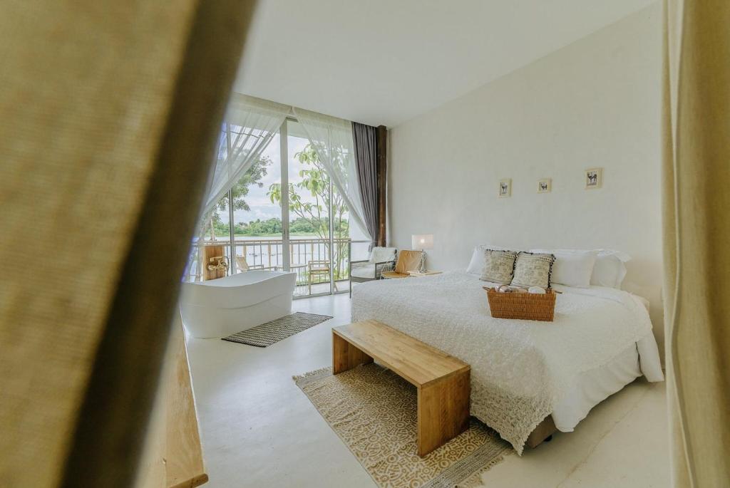 a white bedroom with a bed and a table at White Wall Riverfront Hotel in Kamphaeng Phet