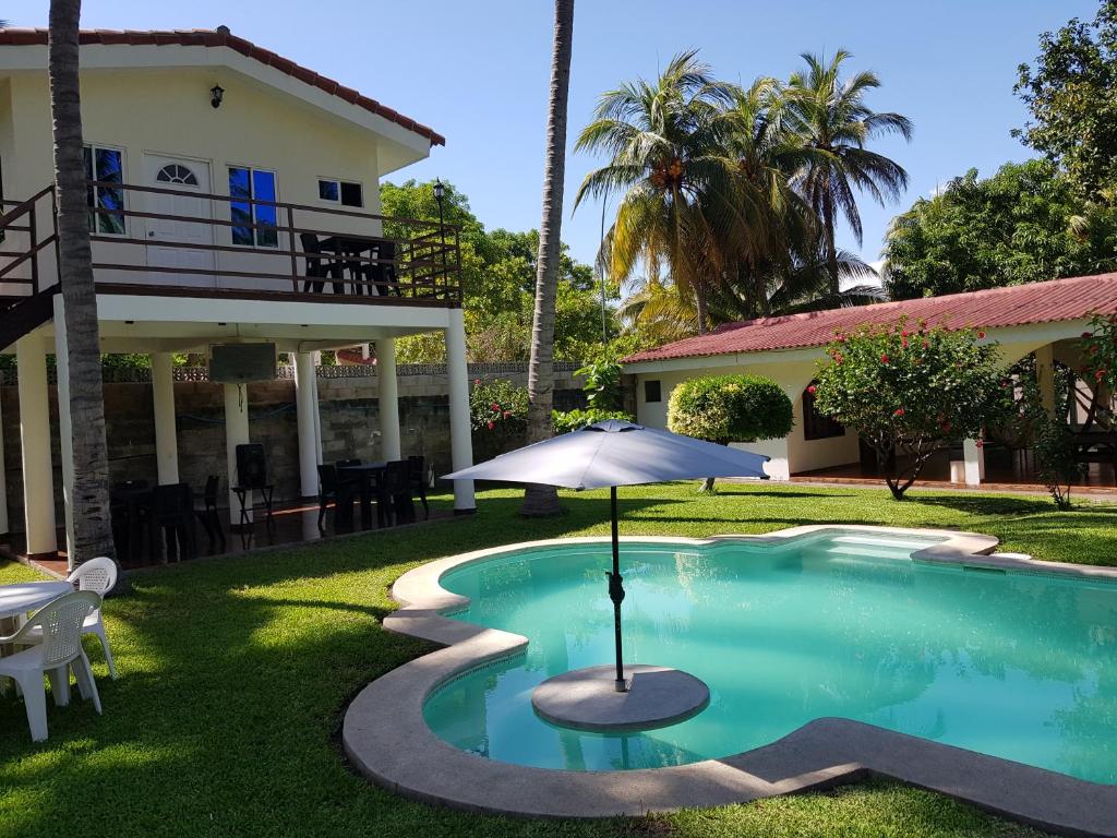 una piscina frente a una casa con sombrilla en Rancho villas de alicia, en La Paz