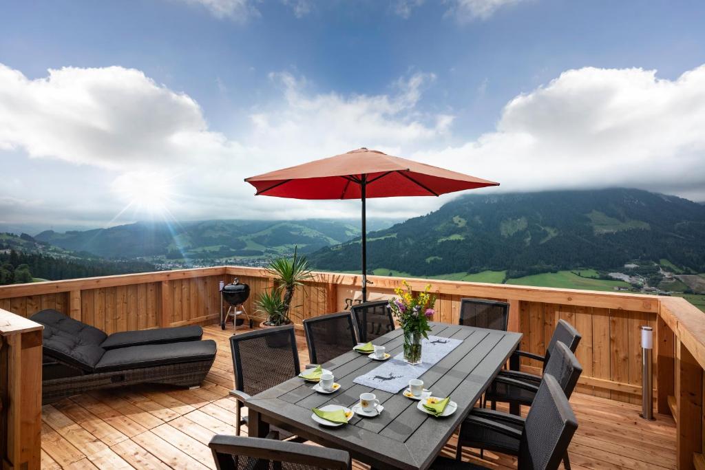 eine Holzterrasse mit einem Tisch und einem Sonnenschirm in der Unterkunft Ferienwohnung Bergwelt in Kirchberg in Tirol