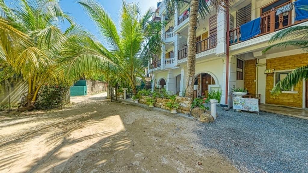a large house with palm trees in front of it at Sky Garden Mini Hotel in Mirissa