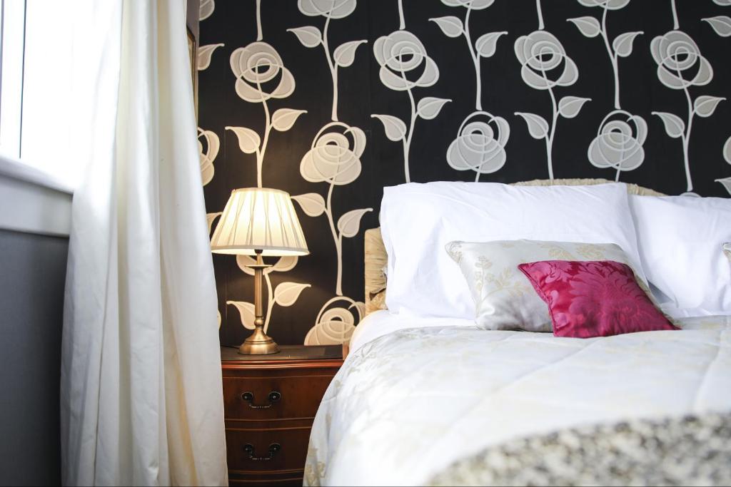 ハミルトンにあるExecutive Suite 2 Bedrms 2 Bath plus Jacuzziのベッドルーム1室(白黒の花柄の壁紙のベッド1台付)