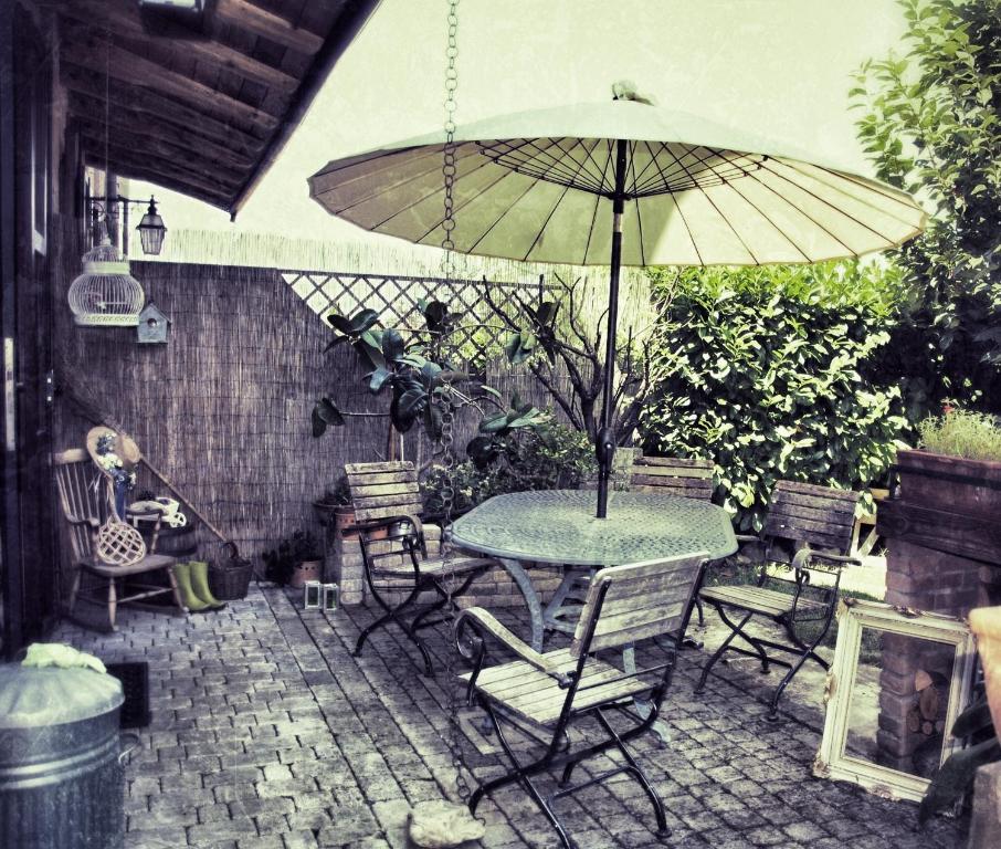 une terrasse avec une table, des chaises et un parasol dans l'établissement La Corte del Macero, à Castelfranco Emilia