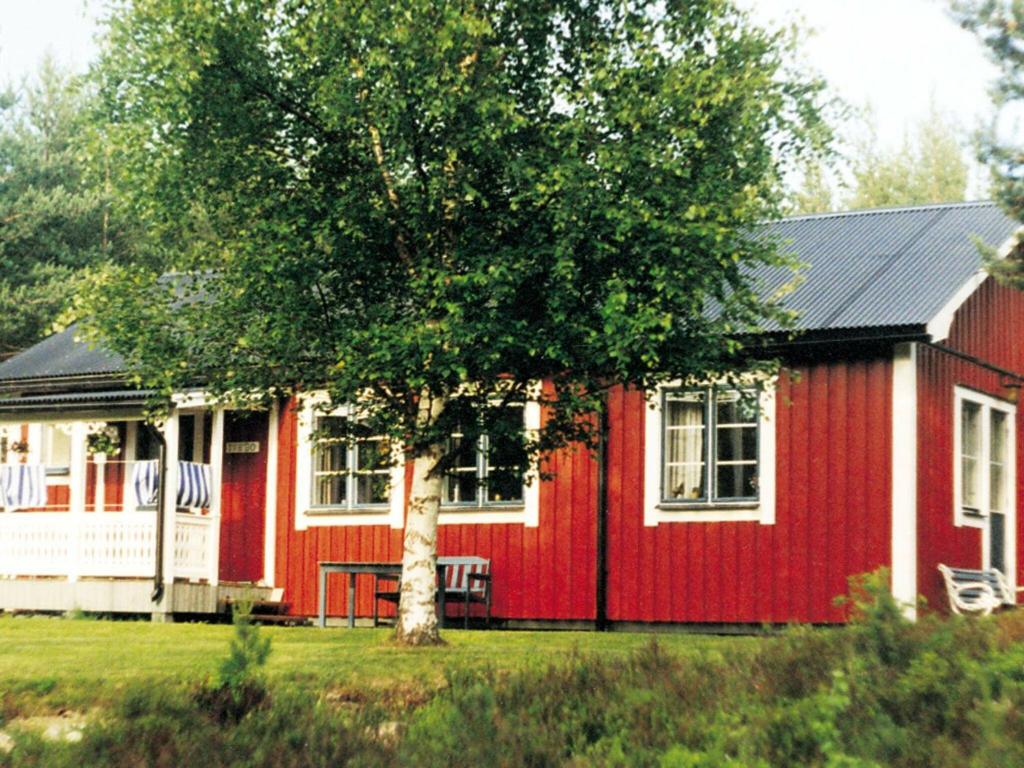 una casa roja con un árbol delante en 6 person holiday home in STMARK en Kristinefors